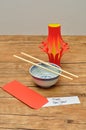 A homemade lantern display with a pair of chopsticks, a bowl and a red envelope with a note Happy New Year