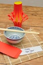 A homemade lantern display with a pair of chopsticks, a bowl and a red envelope with a note Happy New Year