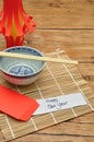 A homemade lantern display with a pair of chopsticks, a bowl and a red envelope with a note Happy New Year