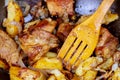 A large grilled pork served in a pan with onion, roasted potatoes