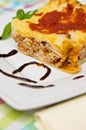 Homemade lasagna on white plate and colorful tablecloth