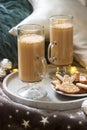 Homemade latte in glass cups, served with gingerbread on the background of plaid, pillows and garlands. Royalty Free Stock Photo