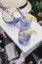 Homemade lavender lemonade with fresh lemons on a white wooden tray