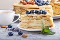 Homemade layered Napoleon cake with milk cream. Decorated with blueberry, almonds, walnuts, hazelnuts, mint on a gray concrete Royalty Free Stock Photo