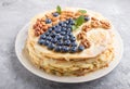 Homemade layered Napoleon cake with milk cream. Decorated with blueberry, almonds, walnuts, hazelnuts, mint on a gray concrete