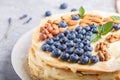 Homemade layered Napoleon cake with milk cream. Decorated with blueberry, almonds, walnuts, hazelnuts, mint on a gray concrete