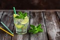 Homemade lemonade in a glass with lime, mint leaves, straw and ice on a dark wooden table. Summer refreshing drink. Selective Royalty Free Stock Photo