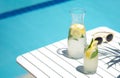 Homemade lemonade in glasses with lemon slice, on white table,in the edge of the pool with turquoise blue water Royalty Free Stock Photo