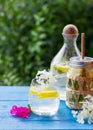 Homemade lemonade with lemon and ice cubes in a glass pitcher on the blue wood table with white and pink flowers Royalty Free Stock Photo