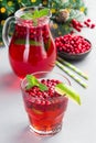 Homemade lingonberry and lime punch or limeade in a glass and pitcher, christmas tree decoration with bokeh, vertical Royalty Free Stock Photo