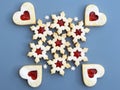 Homemade linzer cookies filled with strawberry jam, small sugar snowflakes around Royalty Free Stock Photo