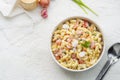 Homemade macaroni salad with elbow pasta, onion, carrot, tomato, green peas and mayonnaise dressing in a white bowl on a white Royalty Free Stock Photo