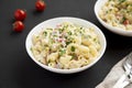 Homemade Macaroni Salad in a white bowl on a black background, side view