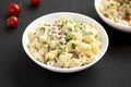 Homemade Macaroni Salad in a white bowl on a black background, side view Royalty Free Stock Photo