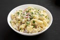 Homemade Macaroni Salad in a white bowl on a black background, side view. Close-up Royalty Free Stock Photo