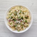 Homemade Macaroni Salad in a white bowl on a white wooden surface, top view. Flat lay, overhead, from above Royalty Free Stock Photo