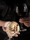 Homemade macaroons in a glass and a glass with young red wine are held in hands. Selective focus on a glass with cookies. Shallow