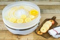 Homemade machine to dehydrate food with orange slices and kitchen table with apple slices