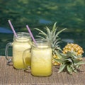 Homemade mango and pineapple smoothie made with coconut milk in two glass mug near swimming pool, close up. Refreshing tropical fr Royalty Free Stock Photo