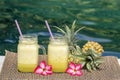 Homemade mango and pineapple smoothie made with coconut milk in two glass mug near swimming pool, close up. Refreshing tropical fr Royalty Free Stock Photo