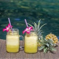 Homemade mango and pineapple smoothie made with coconut milk in two glass mug near swimming pool, close up. Refreshing tropical fr Royalty Free Stock Photo