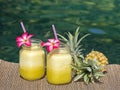 Homemade mango and pineapple smoothie made with coconut milk in two glass mug near swimming pool, close up. Refreshing tropical fr Royalty Free Stock Photo