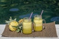 Homemade mango and pineapple smoothie made with coconut milk in two glass mug near swimming pool . Island Bali, Indonesia. Royalty Free Stock Photo