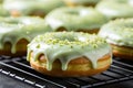 Homemade matcha green tea doughnuts covered with green matcha powder graze and grated pistachio on a cooling rack, close up.