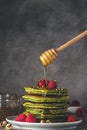 Homemade matcha pancakes with fresh raspberries, pistachios and flowing honey on dark background. low key Royalty Free Stock Photo