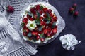 Homemade meringue cake Anna Pavlova with straeberries and mint on the knitted tablecloth. Porcelain Ballerina on dark background.