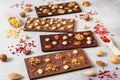 Homemade milk and dark chocolate bars with dried berries and nuts on light background. Side view. Chocolatier work