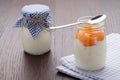 Homemade milk yogurt with fruit jam in glass pot on table