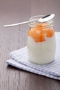 Homemade milk yogurt with fruit jam in glass pot on table
