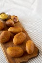 Homemade Mini Corn Dogs on a rustic wooden board on cloth, side view. Copy space