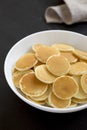 Homemade Mini Pancakes Cereal in a white bowl on a black surface, side view Royalty Free Stock Photo