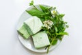 Homemade mint marshmallows on a plate with bouquet of garden plants on white background