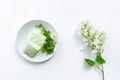 Homemade mint marshmallows on a plate with bouquet of garden plants, white lilac branch on white background