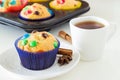 Homemade Muffins with colorful chocolate chips in dark blue paper case and a cup of black tea. White background. Front view Royalty Free Stock Photo