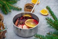 Homemade mulled wine with apple, orange, ginger, cinnamon, cardamom and star anise in a saucepan on a gray background. Royalty Free Stock Photo