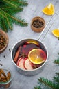 Homemade mulled wine with apple, orange, ginger, cinnamon, cardamom and star anise in a saucepan on a gray background. Royalty Free Stock Photo