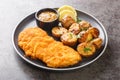 Homemade Munich veal schnitzel fried in breadcrumbs with mustard and horseradish garnished with baked potatoes close-up in a plate