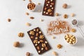 Homemade natural dark chocolate bars and nuts on white background. Side view, copy space. Chocolatier work Royalty Free Stock Photo