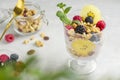 Homemade natural dessert. Granola with raspberries, blueberries, golden kiwi and mint sprig. A glass of muesli, berries and a