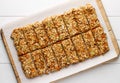 Homemade no bake granola bars with oat flakes, honey, dried apricots and seeds on white baking paper.