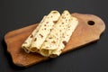 Homemade Norwegian Potato Flatbread Lefse with Butter and Sugar on a rustic wooden board on a black background, side view