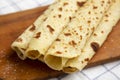 Homemade Norwegian Potato Flatbread Lefse with Butter and Sugar on a rustic wooden board on cloth, side view. Close-up