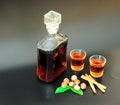 Homemade nut liqueur with cinnamon and mint on a black background, next to a bottle and two glasses of a drink Royalty Free Stock Photo