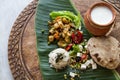 Homemade nutritional vegetable ragout, rice, salad, yogurt, chapati on banana leaf.