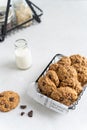 Homemade oatmeal cookies with banana, oats, chocolate drops and nuts on a wooden board and a bottle of milk on a white background