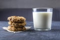 Homemade oatmeal cookies with raisins and chocolate and glass of milk on dark background. Healthy snack for kids before bedtime